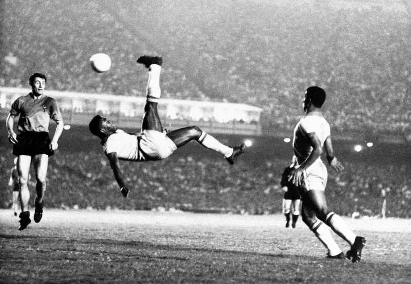 Astro do futebol brasileiro Pelé chuta uma bola de bicicleta durante um jogo em local desconhecido, em setembro de 1968