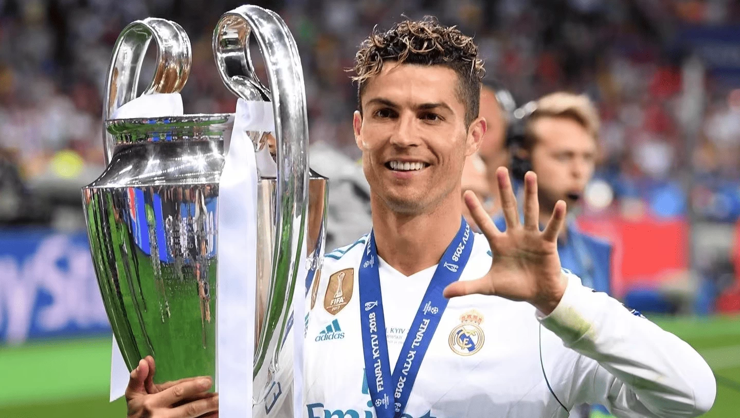 Cristiano Ronaldo, um dos jogadores com mais títulos da Champions League, segurando o troféu do campeonato e fazendo o número 5 com a mão