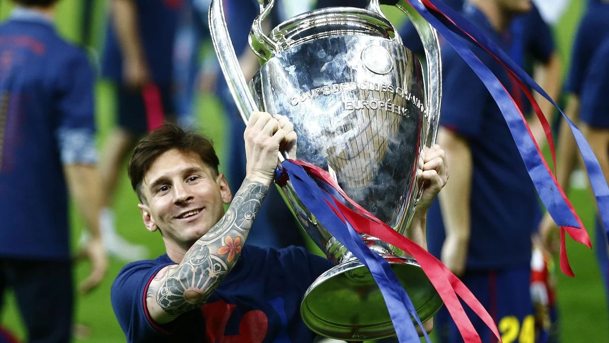 Messi, um dos jogadores com mais títulos da Champions League, sorrindo e segurando a taça do campeonato