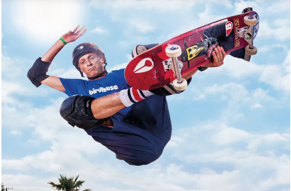 Foto do Skatista Tony hawk realizando uma manobra no ar com seu Skate