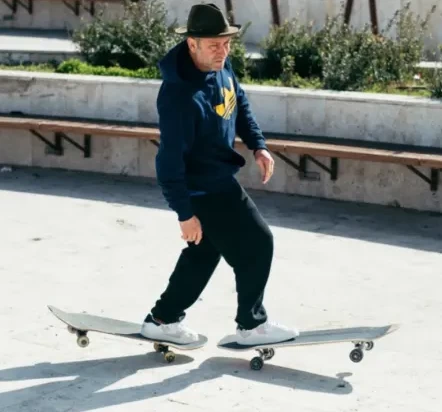 Mark Gonzales em cima de dois skates em uma rua