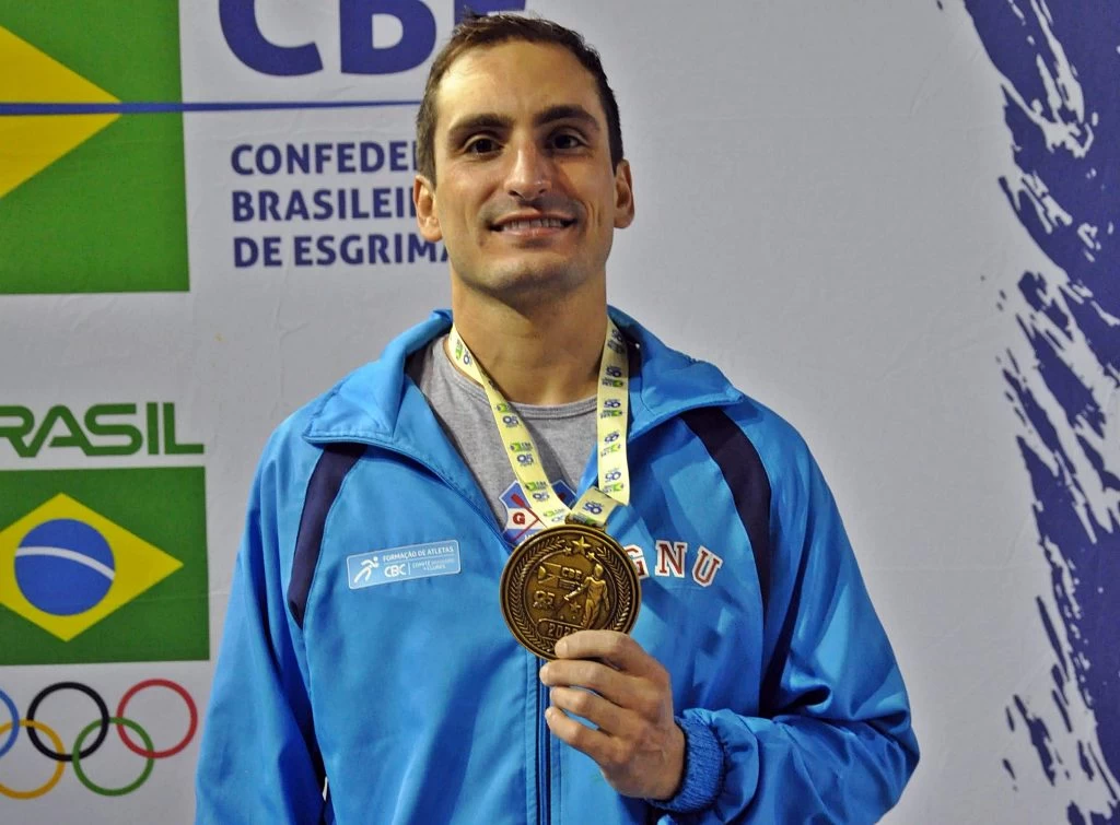 Guilherme Toldo, esgrimista brasileiro, comemora sua vitória segurando o troféu