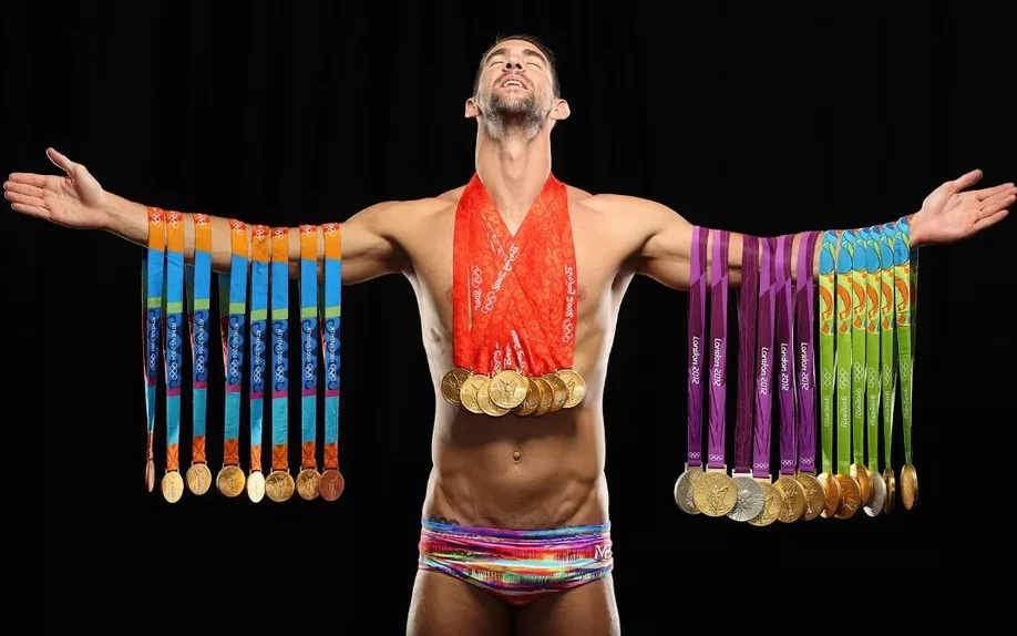 Nadador Michael Phelps segurando todas as medalhas conquistadas durante suas participações nas Olimpíadas