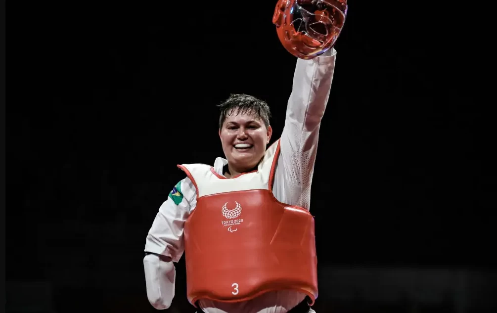 Débora Menezes, uma das maiores atletas paralímpicas do Brasil, em pé e segurando sua medalha de prata