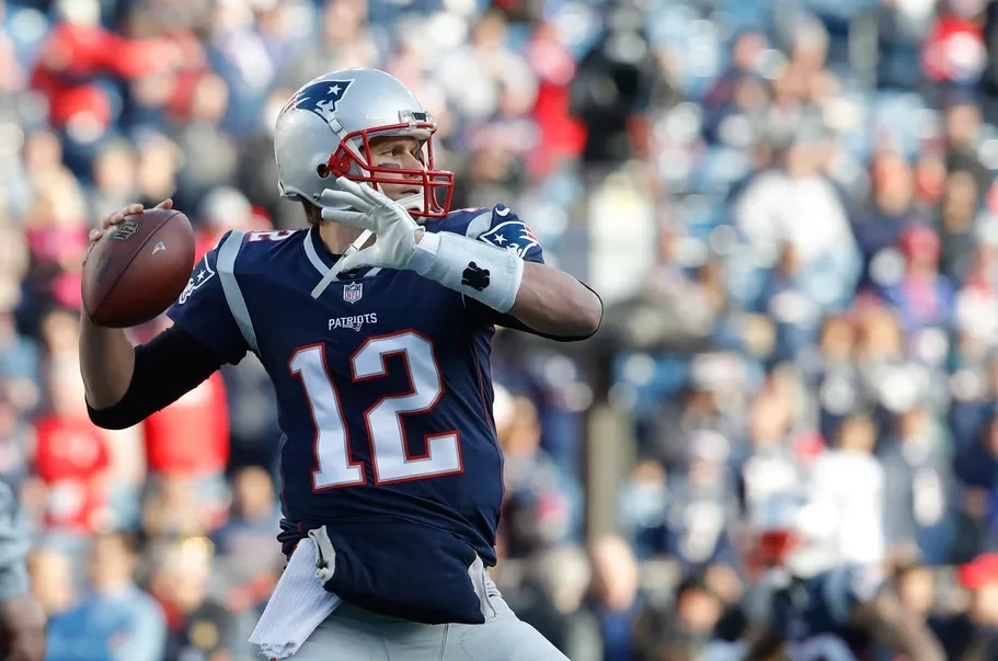 Tom Brady, uma das lendas da NFL, em campo segurando uma bola de futebol americano