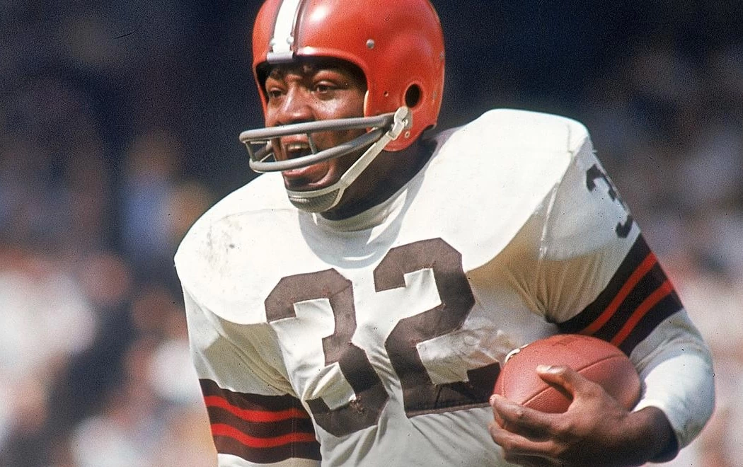 Jim Brown, uma das lendas da NFL, em campo e em posição de ataque, com a camisa número 32