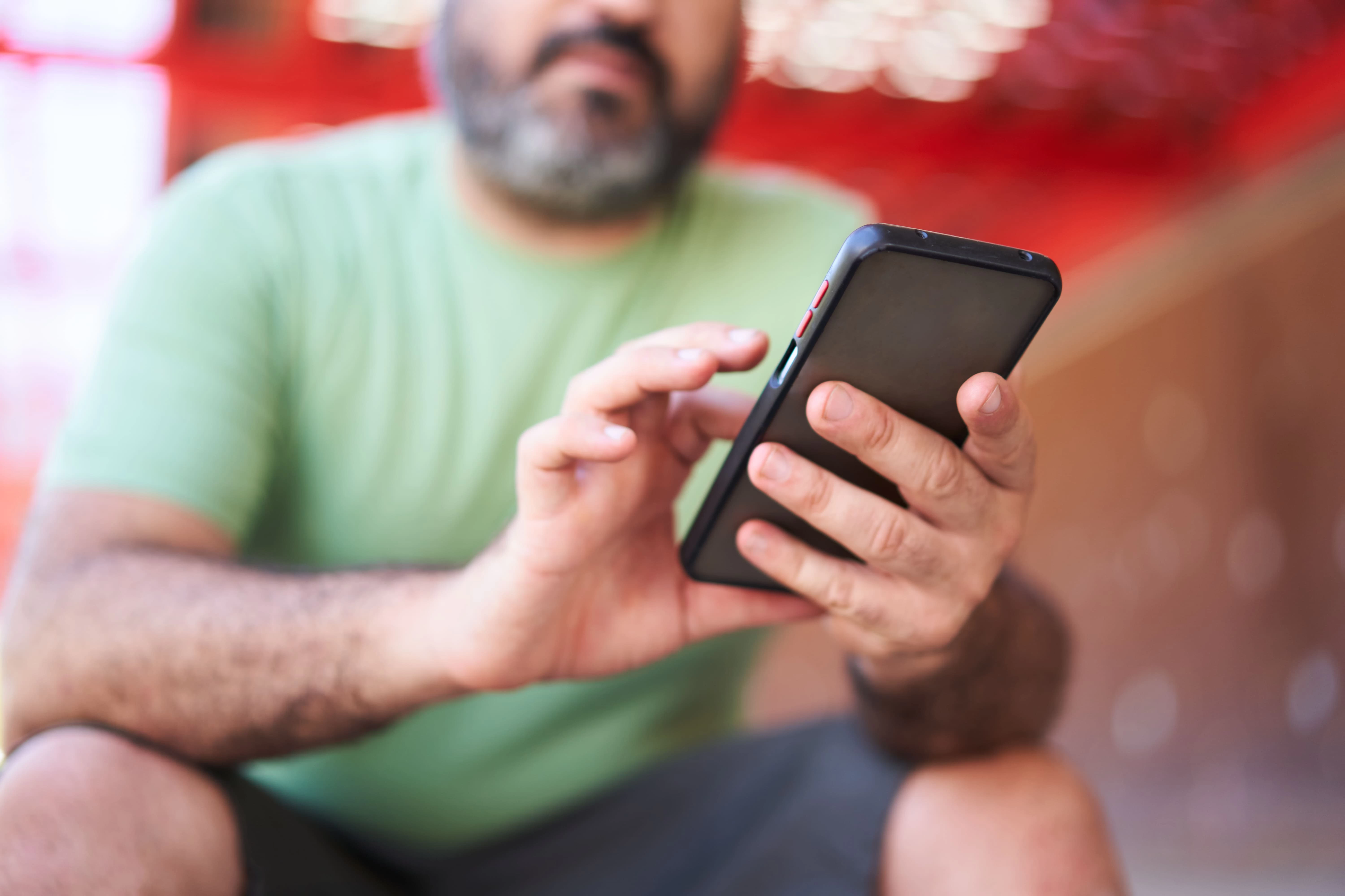 homem sentado no sofá mexendo no celular